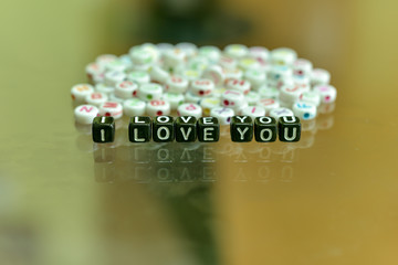 I LOVE YOU  written with Acrylic Black cube with white Alphabet Beads on the Glass Background