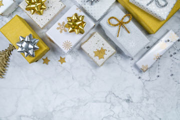 Christmas concept - silver and gold presents with confetti anf ribbon, marble background, top view