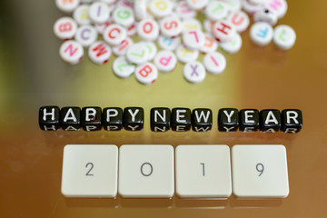 HAPPY NEW YEAR 2019 written with Acrylic Black cube with white Alphabet Beads on the Glass Background