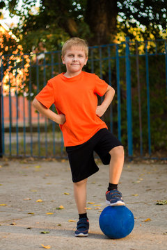 the boy, a student in an orange shirt playing soccer on the Playground
