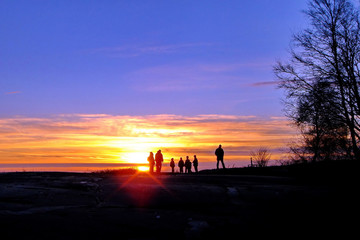 Fototapeta na wymiar Dark silhouettes of people on winter sunset background