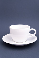 Ceramic white cup on saucer on grey background. Mock up for design.