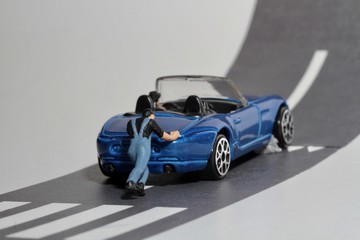 miniatura di uomo che aiuta un automobilista in panne con l'auto