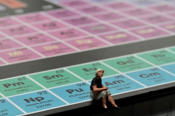 miniatura di persona seduta su tavola periodica degli elementi chimici
