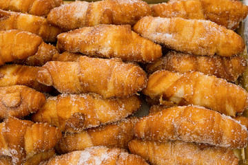 Bunch of freshly baked delicious deep fried croissants cronuts dusted with sugar. Appetizing golden crust. American pastry. Baking unhealthy diet concept