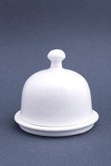 Ceramic white closed butter-dish on grey background. Mock up for design.