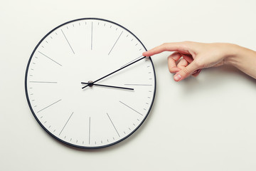 Woman hand stop time on a round clock, time management and deadline concept