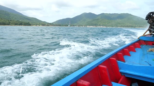 Traditional Thail long-tail boat, floats and move  forward in the middle of the sea. Wooden motor boat floating in the clear water