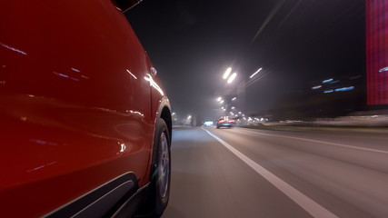 Driving urban look from fast driving car at a night avenue in a city