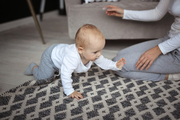 Naklejka premium Mom plays with baby in real interior communication