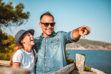 Father and daughter standing by the sea and looking into horizon