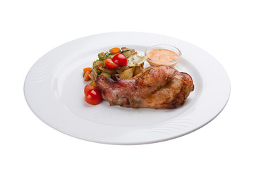 Chicken leg with baked vegetables. On a white plate