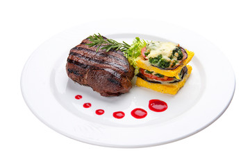 Beef steak with grilled vegetables and an omelette. On a white plate
