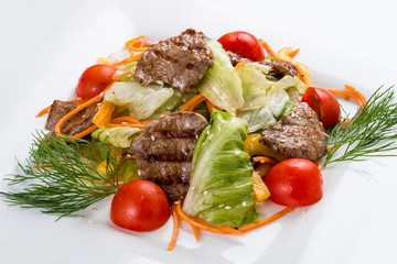 Medallions of veal with vegetables and salad. On a white plate