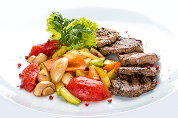Medallions of veal with vegetables and salad. On a white plate