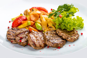 Medallions of veal with vegetables and salad. On a white plate
