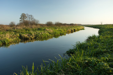 Green grassy shore and calm river.