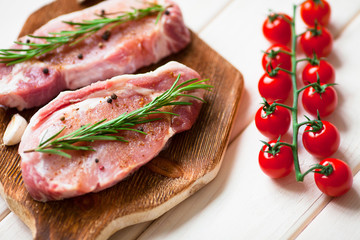 Fresh raw pork on the cutting board with ingredients for cooking. Food, flat lay, recipes and nutrition concept. Top view. Close up.