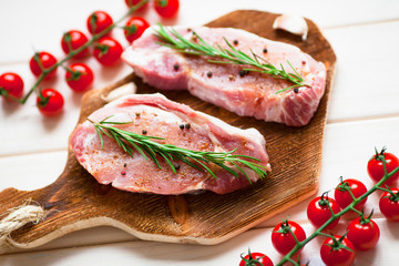 Fresh raw pork on the cutting board with ingredients for cooking. Food, flat lay, recipes and nutrition concept. Top view. Close up.