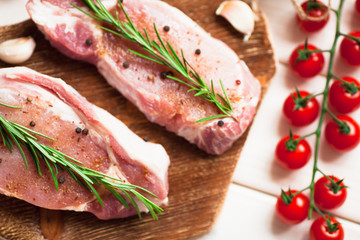 Fresh raw pork on the cutting board with ingredients for cooking. Food, flat lay, recipes and nutrition concept. Top view. Close up.