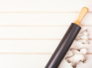 rolling pin and cookie cutters on the white wooden background.