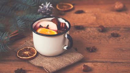 Mulled wine in white rustic mug with spices and citrus fruit