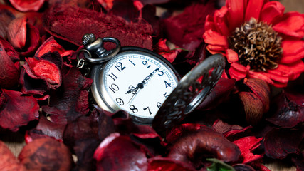 Golden vintage pocket watch put on a wooden table with red dried flowers with aroma