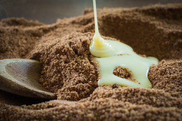 preparing delicious Brazilian sweets called cajuzinho - pouring condensed milk into the mixture of...