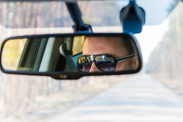 Reflection of man in car rear view mirror