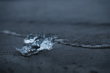 A shiny chunk of melting ice on a seashore.