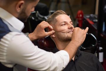Man during procedure of threading beard in barber shop