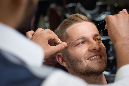 Closeup of process of threading procedure in barber shop