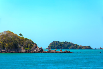 Lighthouse on the shoals of a small island on the way to the Saladan Pier bay in the bright scorching sun with turquoise green blue sea. Adaman sea, Koh Lanta, Krabi, Thailand.