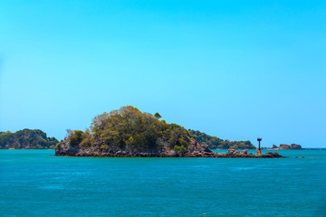 Fototapeta premium Lighthouse on the shoals of a small island on the way to the Saladan Pier bay in the bright scorching sun with turquoise green blue sea. Adaman sea, Koh Lanta, Krabi, Thailand.