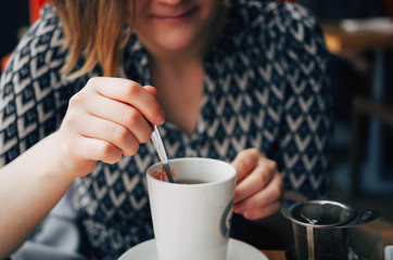 Closeup of a ginger girl preparing a hot cup of tea.