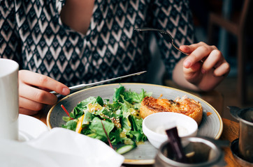 Closeup of a girl eating a beautiful colourful plate of egg quiche and fresh salad.