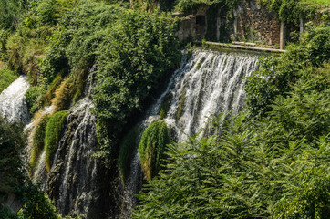 Cascades of waterfalls among ancient ruins in vegetation