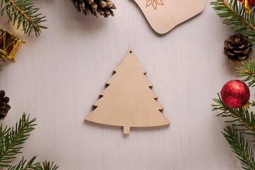 Wooden Christmas tree decoration surrounded by spruce twigs, pine cones and red and golden decorations. Flat lay style