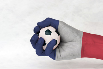 Mini ball of football in France flag painted hand on white background. vertical tricolor of blue...