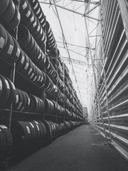 Black and white warehouse fully stacked with car tyres. © LegasC