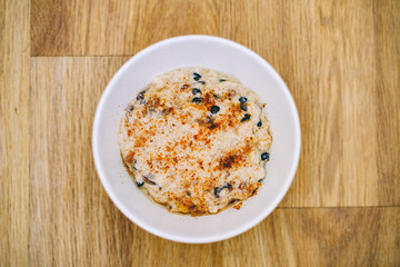 Breakfast porridge in a white bowl with raisins and cinnamon