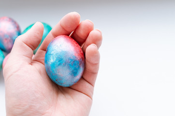 Top view of holding a shiny blue and red easter egg on a white background. 