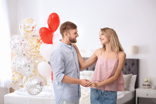 Young couple with air balloons in bedroom. Celebration of Saint Valentine's Day