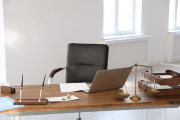 Scales of justice, laptop and wax stamp on desk in notary's office