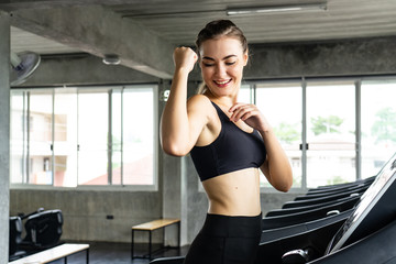 Cute young woman exercising on  treadmill at a gym.Active young woman running on treadmill. smile and funny emotion.