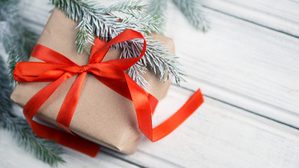 gift box with red ribbon on white background with Christmas tree branches in snow
