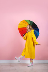 Woman with rainbow umbrella near color wall