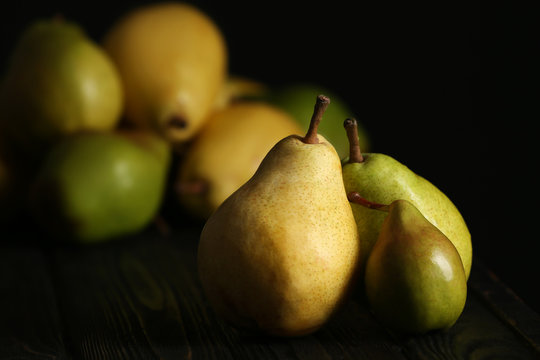 Fresh ripe pears on dark table against blurred background