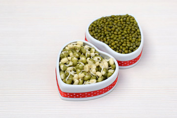 Dry and sprouted mung beans in ceramic bowls of heart shape