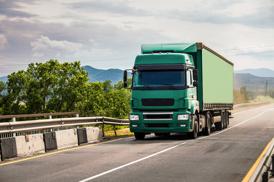 Green semi-truck moving over the bridge
